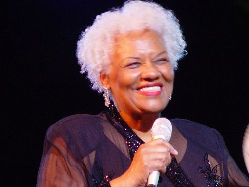 A woman with white hair holding a microphone.