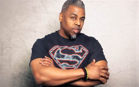 A man with his arms crossed wearing a superman shirt.