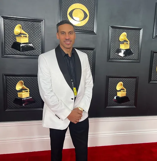 A man in white jacket standing on red carpet.