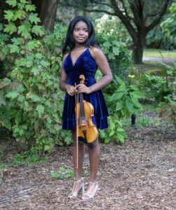 A woman in blue dress holding a violin.