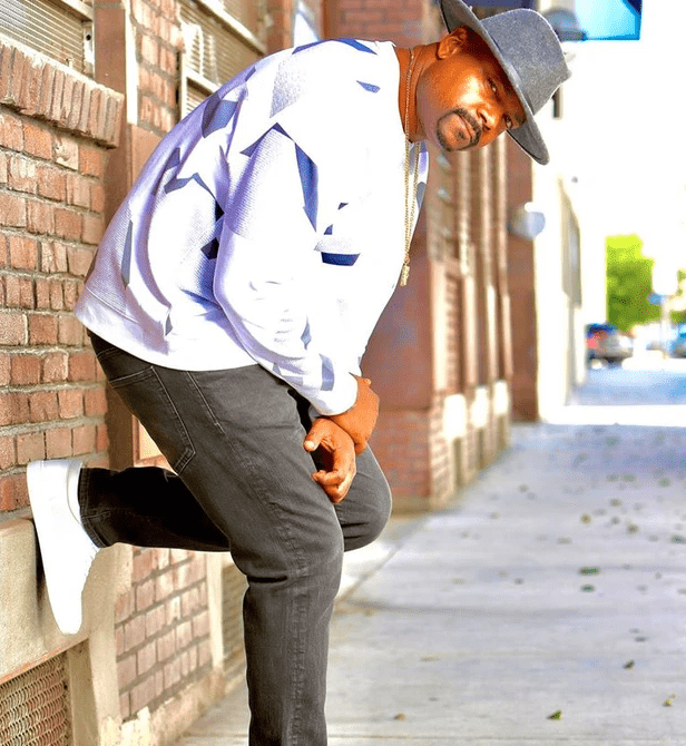 A man leaning against the side of a brick wall.