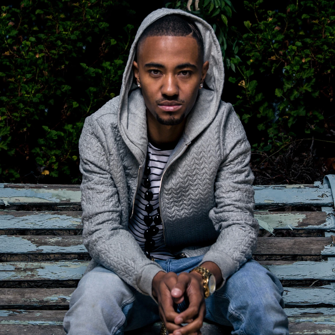 A man sitting on top of a bench wearing a hoodie.