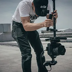 A man holding a camera on top of a tripod.