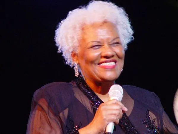 A woman with white hair holding a microphone.