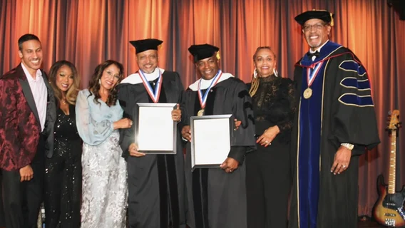 A group of people in graduation attire holding certificates.