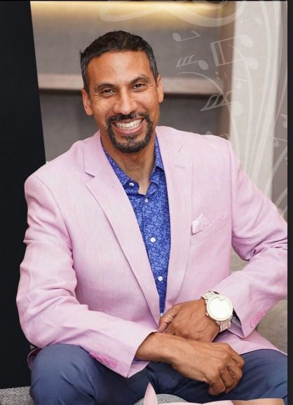 A man in a pink suit smiling for the camera.